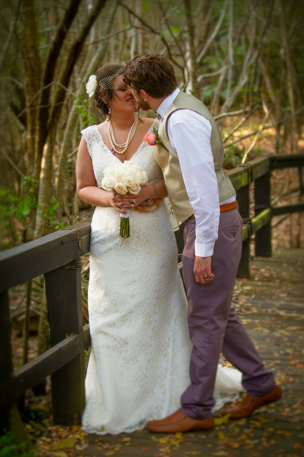A wedding couple standing together on a wooded bridge